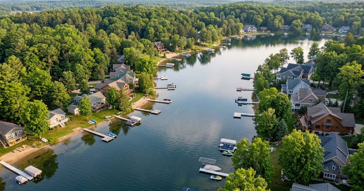 Aerial view of Southwest Michigan lake homes with docks and boats on calm water surrounded by dense green trees